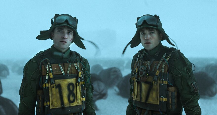 Two identical men in survival outfits stand on a snowy plain