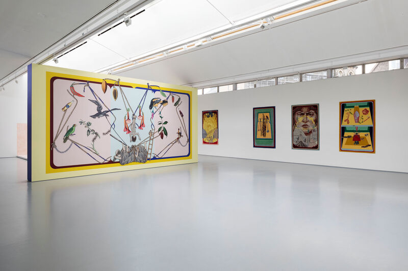 Gallery space with a bright mural and colourful tuftings on the wall