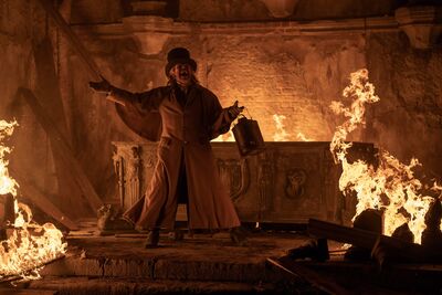 A man stands with his arms out in a burning crypt.