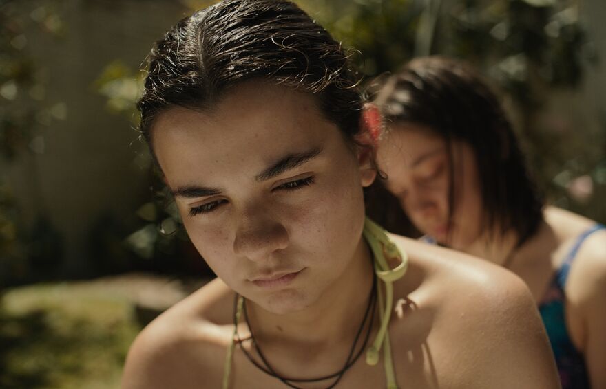 A girl with dark hair wears a swimsuit in the sun but looks troubled