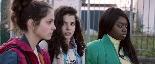 Three teen girls talk seriously in a school yard