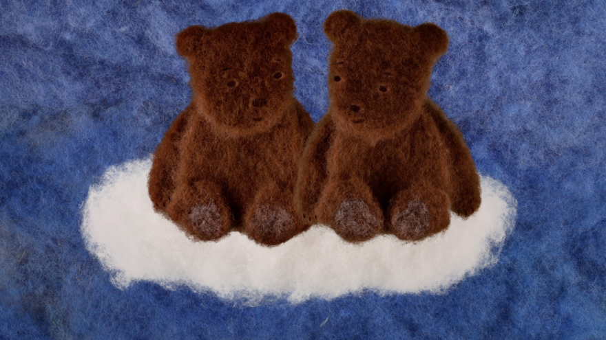 Two little felted brown bears sit on a cloud.