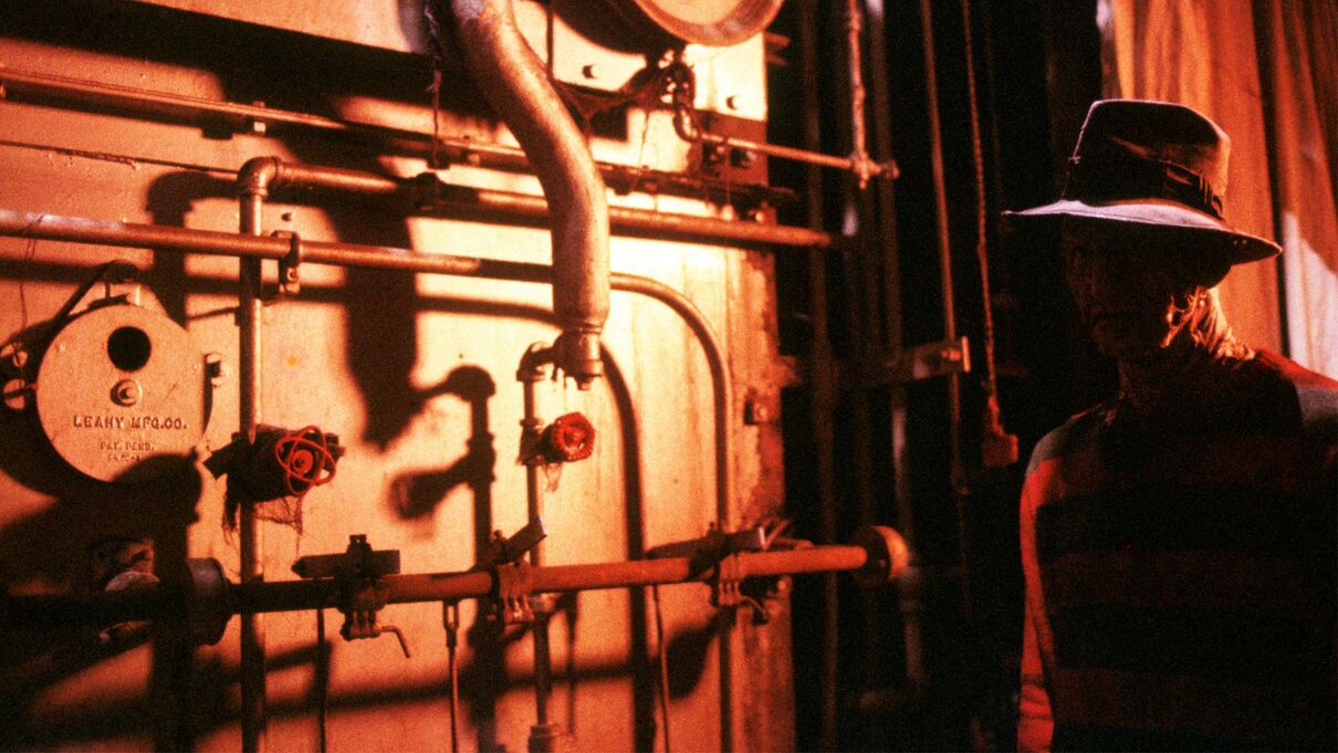 Freddy Krueger standing in shadow beside boiler room equipment