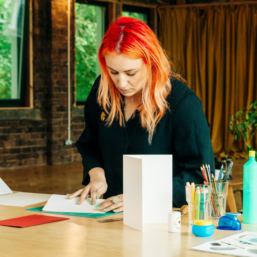 Woman with orange hair folding paper