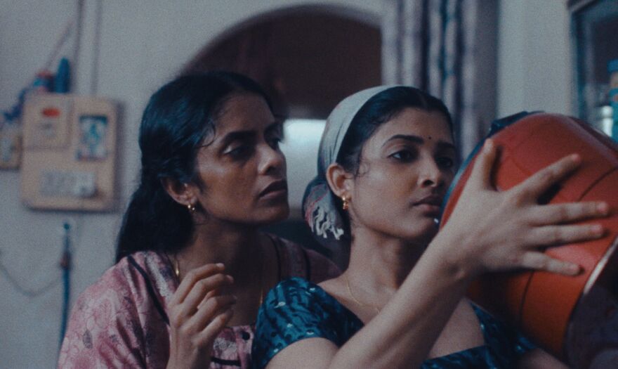 Two women look at the bottom of a pot.