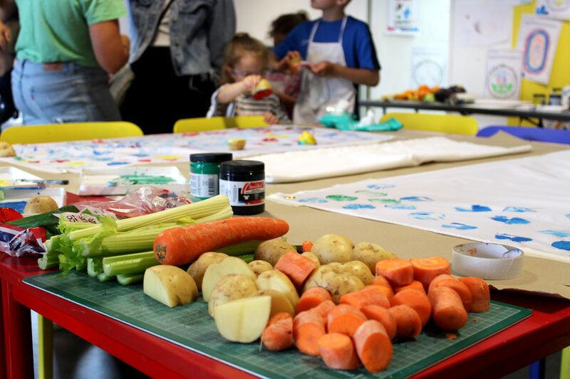 Vegatables on a table with children in the backgrund using them to print with