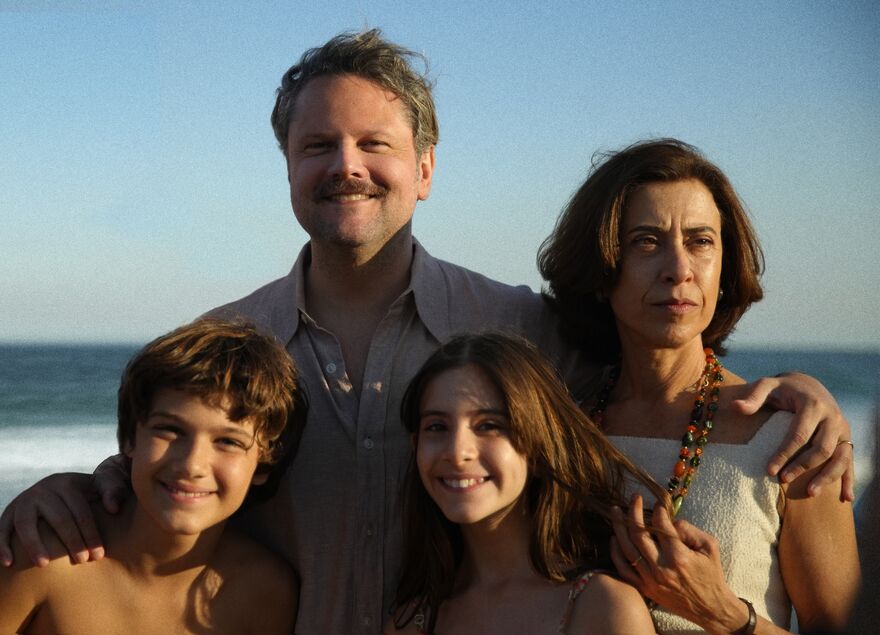 A family stand on the beach, with parents and two young children.